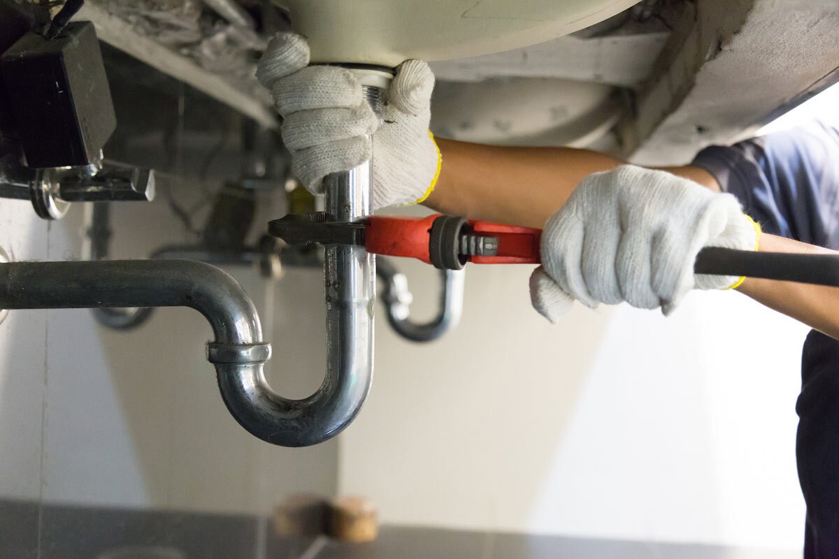 plumber fixing a leaking pipe under a bathroom sink