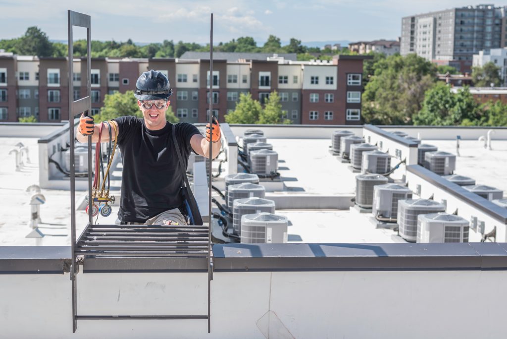 man climbs onto roof to service commercial hvac unit