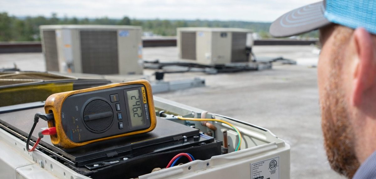 Commercial HVAC technician repairing rooftop AC unit in Tulsa OK for office, warehouse, and retail building cooling service
