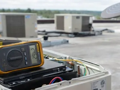 Commercial HVAC technician repairing rooftop AC unit in Tulsa OK for office, warehouse, and retail building cooling service